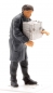 Preview: Man in smock putting down box -0-